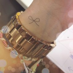 a person with a tattoo on their wrist holding onto a gold watch band and bracelet