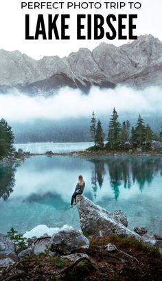 a person sitting on top of a rock next to a lake