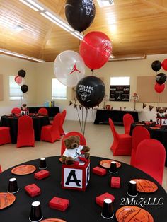 a room filled with red chairs and black table cloths, balloons in the shape of letters