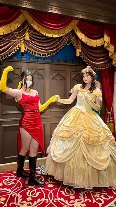 two women dressed as princesses posing for the camera in front of a stage curtain