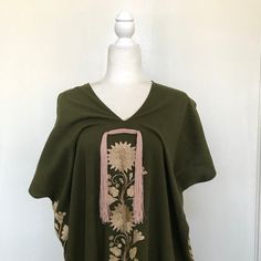 This hand-woven two panel Mexican Yalalag Hupil long tunic is a VINTAGE CLASSIC with flowers embroidered by hand by artisans of Oaxaca 100% handmade. A relaxed style and at the same time looks very elegant for a party in the morning or afternoon. It is made of 100% cotton blanket fabric. MADE IN MEXICOBy: Mexican ArtisansFor: Women Size: M/L Color: khaki green | gold Length: 41.5" Details: Material: cotton silk Non-stretch Embroidered thread Front & back tassels Ankle Length Washing Instructions Folk Style Poncho With Floral Embroidery, Traditional Tunic For Spring, Traditional Free Size Tunic For Spring, Bohemian Embroidered Summer Poncho, Embroidered Bohemian Poncho For Summer, Traditional Green Tunic With Floral Embroidery, Blanket Fabric, Flowers Embroidered, Cotton Blanket