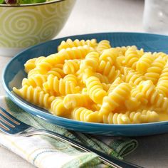 a blue bowl filled with macaroni and cheese on top of a table