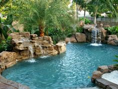 an outdoor pool with waterfall and palm trees