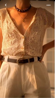 a woman wearing white shorts and a crochet top with a brown belt around her waist