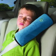 a young boy sleeping in the back seat of a car with a pillow on his arm