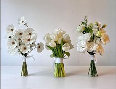 three vases filled with white flowers on top of a table