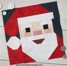 a quilted santa claus face on top of a red and black piece of fabric