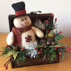 a stuffed snowman sitting in a suitcase on a table