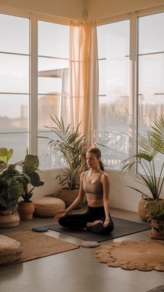 a woman is sitting in a yoga pose with her legs crossed and looking out the window