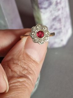 a woman's hand holding an old fashioned ring with a red stone in it