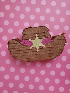 a paper cowboy hat on top of a pink polka dot background