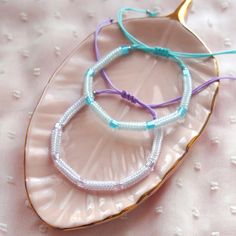 three bracelets sitting on top of a pink plate next to a white tablecloth