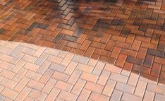 an umbrella is sitting on the ground next to a brick walkway and bench with no people around it