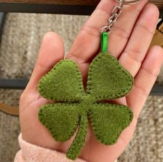 a hand holding a key chain with a green shamrock shaped felt piece attached to it