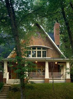 a house in the woods with stairs leading up to it's front door and porch