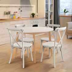 a white table and chairs in a room with hardwood floors, windows, cabinets and an oven