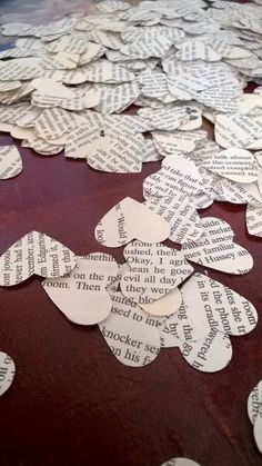 several pieces of paper cut into hearts with words written on them sitting on a table