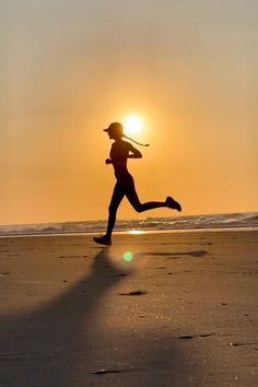 a woman running on the beach at sunset