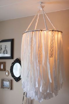 a white chandelier hanging from a ceiling in a room with pictures on the wall