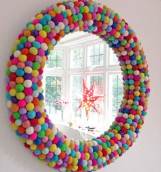 a colorful wreath made out of pom - poms is hanging on the wall