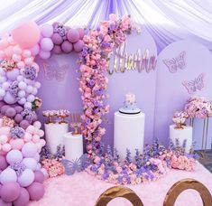 a purple and pink birthday party with balloons, streamers, cake and flowers on the wall