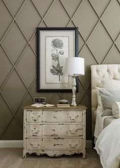 a white bed sitting next to a dresser with a lamp on top of it