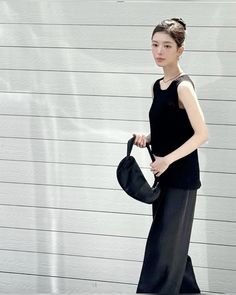 a woman is walking down the street with an umbrella in her hand and wearing black