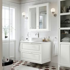 a bathroom with white cabinets and tiled flooring