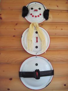 two snowmen made out of plates on a wooden table with black and white trim