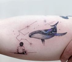 a person sitting on the ground with a whale tattoo on their left arm, and stars in the background