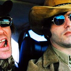 two men wearing cowboy hats and sunglasses sitting in a car, one with his mouth open