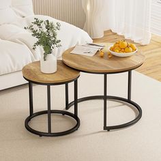 two tables sitting on top of a white carpeted floor next to a bed with pillows