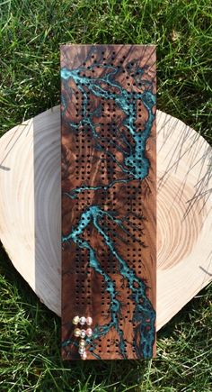 a piece of wood sitting on top of green grass next to a tree stump with blue paint