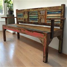 a wooden bench sitting on top of a hard wood floor next to a potted plant