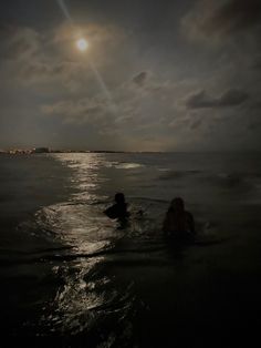 two people swimming in the ocean at night