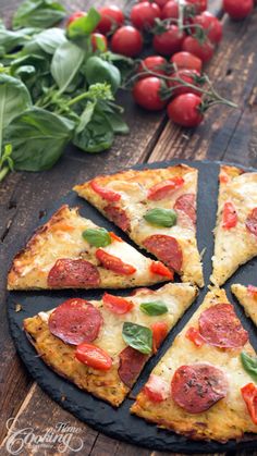 a pizza sitting on top of a pan covered in cheese and toppings next to tomatoes