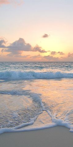 the sun is setting over the ocean with waves coming in