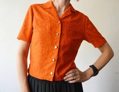 Free shipping worldwide! Please press "Learn more about this item" to read full description and measurements below ↓. Pumpkin orange cropped cotton shirt with golden buttons, small collar and short sleeves. Has tiny botanical print all over. Brand: not stated, possibly handmade Material: feels like cotton Size: estimated M Condition: great vintage condition, save for a bit of fraying of the fabric at the edge in front - see last pic Measurements Length - 51 cm/20.1" Shoulder to shoulder - 39 cm/ Orange Short Sleeve Blouse For Fall, Collared Orange Shirt With Buttons, Orange Collared Shirt With Buttons, Orange Short Sleeve Top With Buttons, Orange Cotton Blouse With Button Closure, Vintage Orange Blouse For Summer, Orange Collared Top With Buttons, Vintage Orange Summer Blouse, Orange Short Sleeve Shirt With Buttons