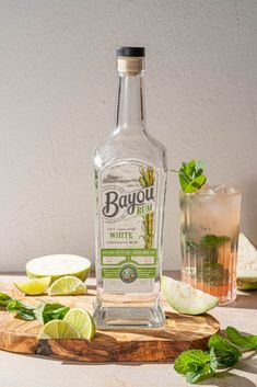 a bottle of bayou white sitting on top of a cutting board next to sliced limes