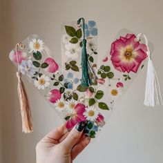 a person holding up some flowers and tassels to show off their jewelry pieces