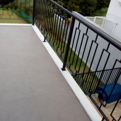 a balcony with black iron railings and blue chairs on the side walk next to it