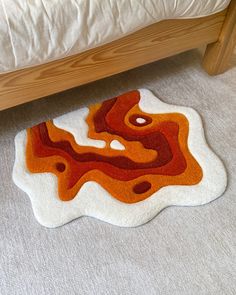 an orange and white area rug on the floor next to a bed with a wooden headboard