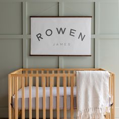 a baby's crib in front of a wall with a name sign above it