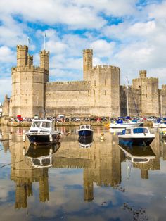 several boats are docked in the water near an old castle