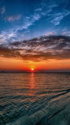 the sun is setting over the water at the beach