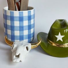 a ceramic cow's head next to a green hat