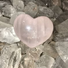 a pink heart sitting on top of some rocks and gravel with ice crystals around it