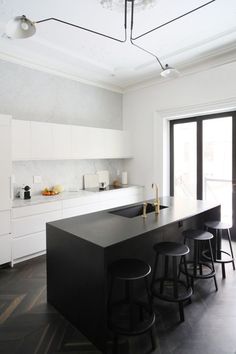 a kitchen with black counter tops and stools next to an open sliding glass door