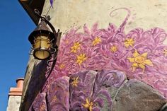 a painting on the side of a building with purple and yellow flowers painted on it