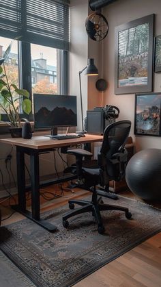 an office with a desk, chair and computer on top of a rug in front of large windows